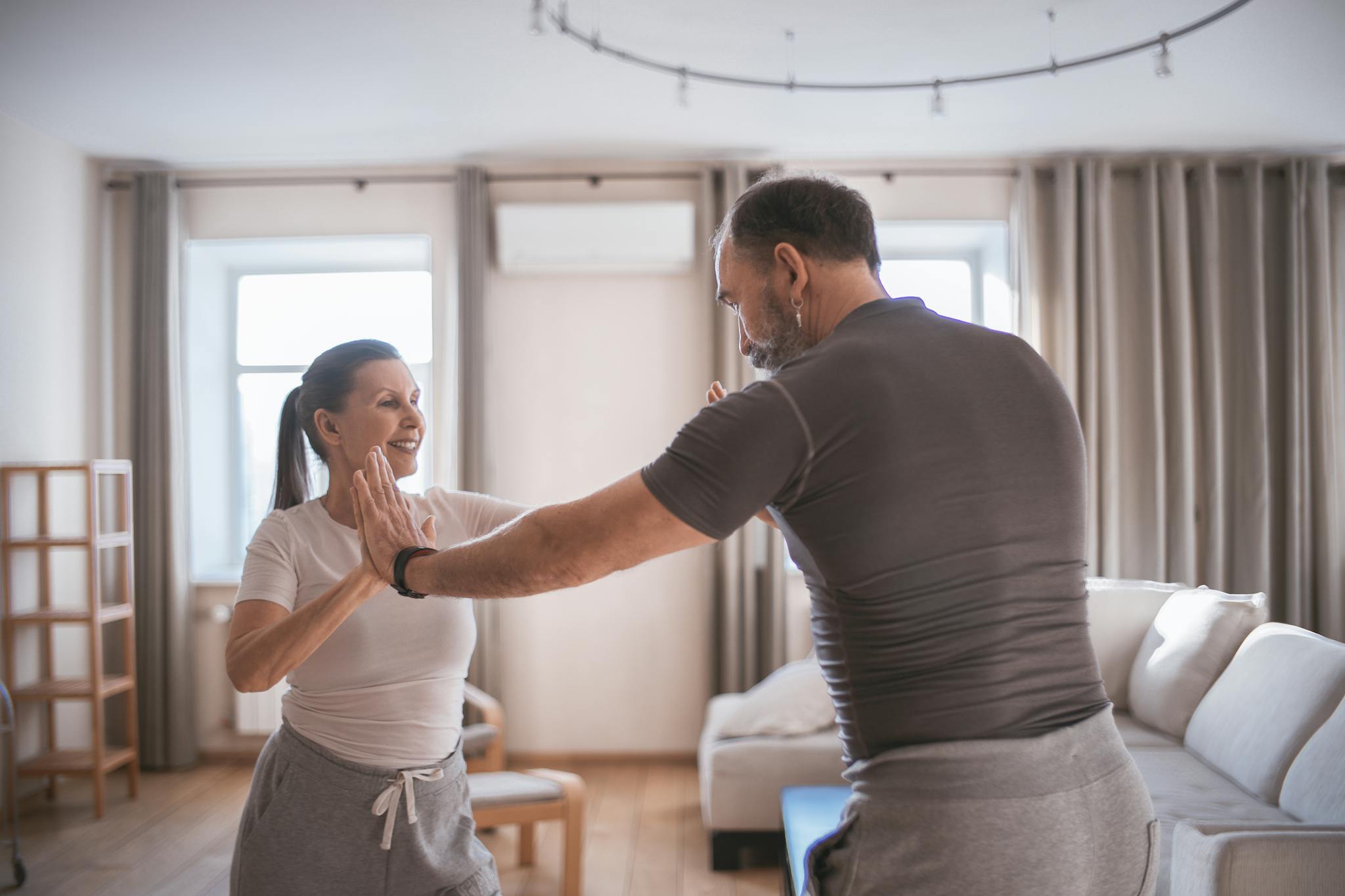 Senior couple engaging in fun exercises together at home, promoting fitness and bonding.